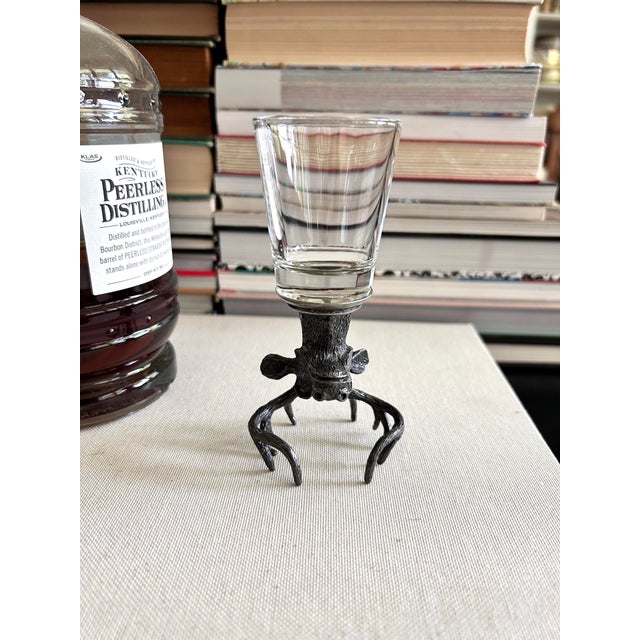 sculptural vintage shot glass featuring a clear glass vessel mounted to a finely detailed pewter-tone stag head. When in...