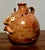 A wonderfully expressive 1990s face jug by folk potter M.J. Wenn, crafted in the lively Southern/Appalachian face‑jug...