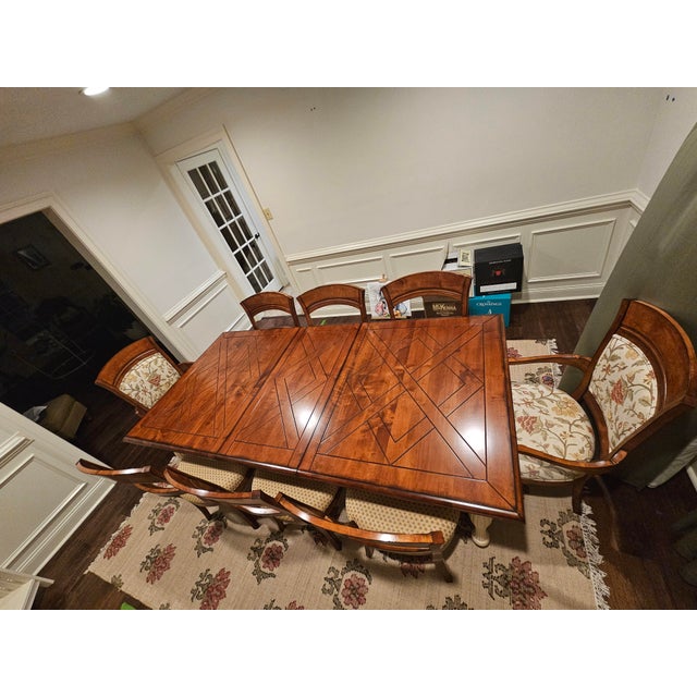 Traditional Solid Wood Dining Table With Geometric Inlay Top and Carved Trestle Legs. Two Captain chairs, 6 other chairs...