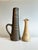 Two slender, tall studio-style ceramic vases made in Germany in the 1980s. The handled vase, in a dark brown with olive...