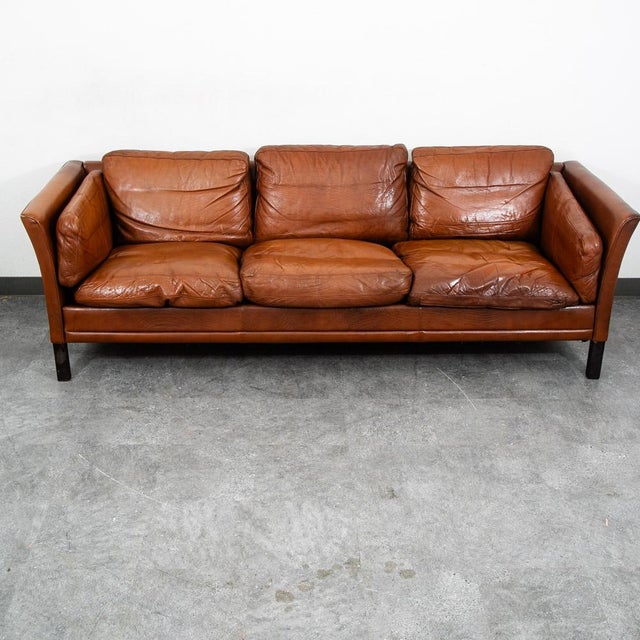 Nicely worn in Danish modern 3 seater cognac leather sofa from the 70s, with wooden legs. The leather is rich and thick...