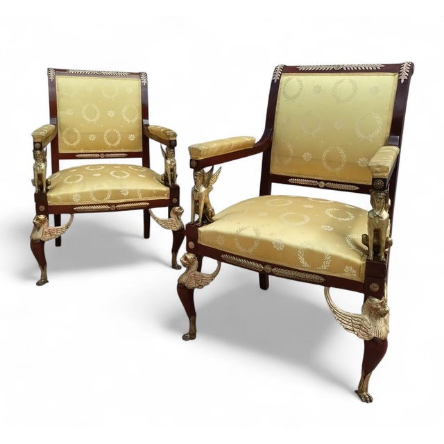 This is a pair of antique French Empire Revival armchairs, crafted from mahogany and decorated with gilded bronzes. The...