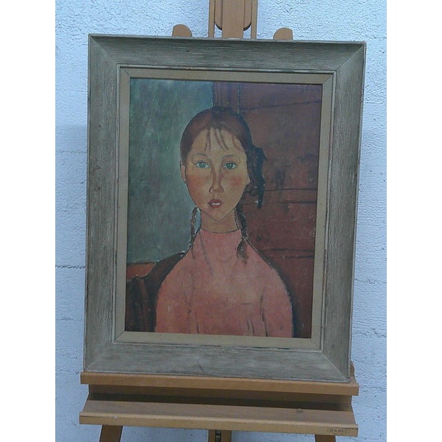 A vintage, reproduction print of "Portrait of a Girl (Victoria)" by Amedeo Modigliani features the artist’s iconic...