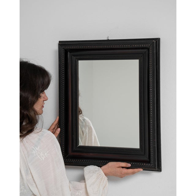 This mirror makes its impression through black frame, rectangular. Originating in France during 20th Century, it shows the...