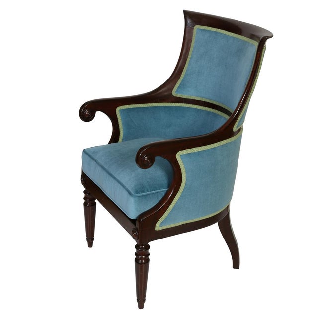 An English Regency style mahogany library armchair distinguished by its refined proportions, gracefully scrolled arms, and...