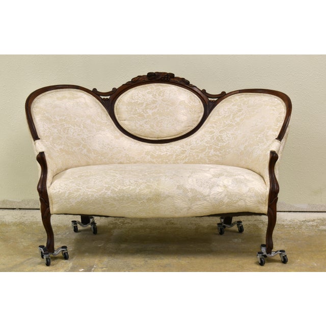 Antique Victorian Damask Settee, dating from the mid-to-late 19th century. It features a carved wooden frame with ornate...