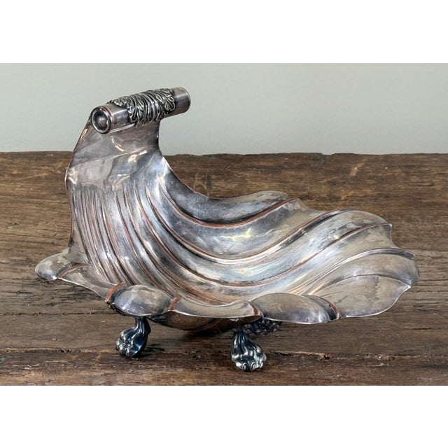Antique silver plate shell-form compote or serving dish raised on three paw feet, with a rolled and chased handle detail...