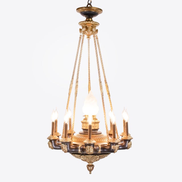 This early 20th-century French neoclassical chandelier is made from patinated bronze and gilt bronze, and brass. The...