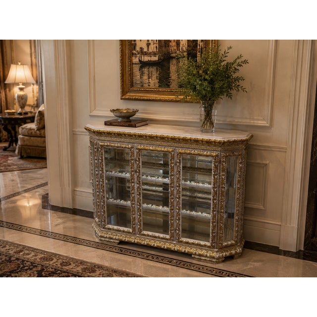 A spectacular statement piece, this richly detailed curio cabinet features an ornate gold and silver-toned finish, a...