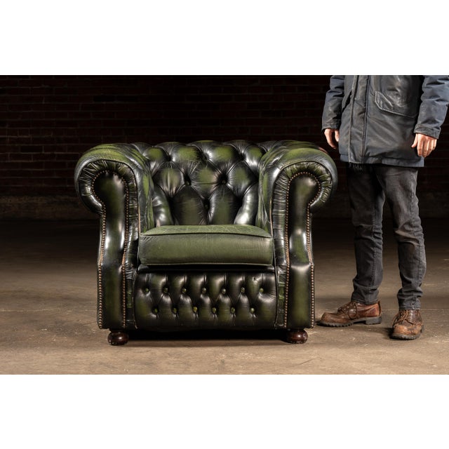 Classic Chesterfield club chair upholstered in deep green leather with a fully button-tufted back and seat rail, rolled...