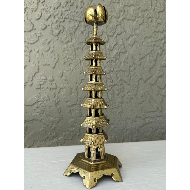 Antique Chinese cast brass candlestick holder in the form of a tall temple or pagoda. It features a thin brass bobeche in...