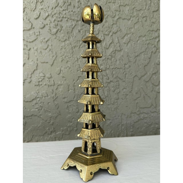 Chinese cast brass candlestick holder in the form of a tall temple or pagoda. It features a thin brass bobeche in the form...