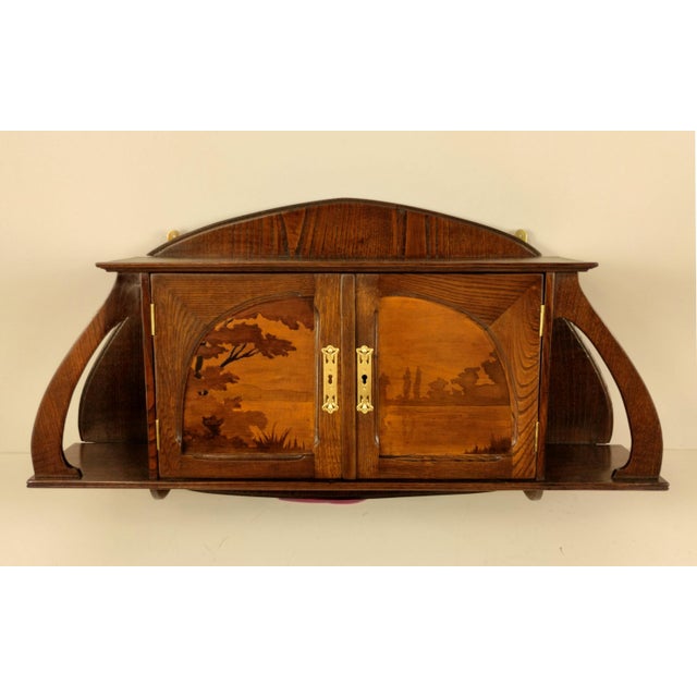 An Art Nouveau wall cabinet made of solid oak in France around 1900. The piece features a characteristic organic shape...