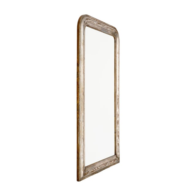 A French Louis Philippe mirror with a softly rounded upper profile and a layered, molded frame finished in distressed...