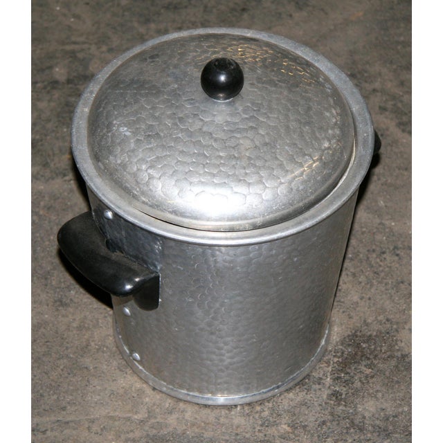 Mid Century aluminum ice bucket featuring a distinctive hammered texture with rivet detailing around the body and black...