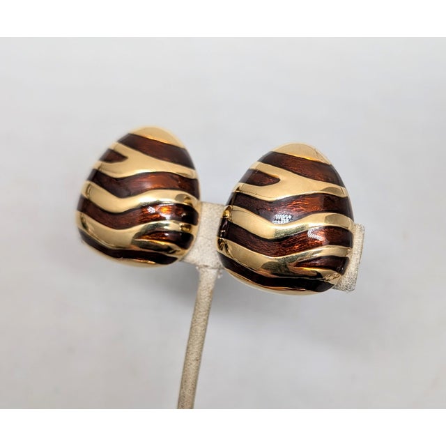 1980s goldtone domed triangular with rounded edges brown enamel striped clip earrings. Marked "CINER®" on the clips and...