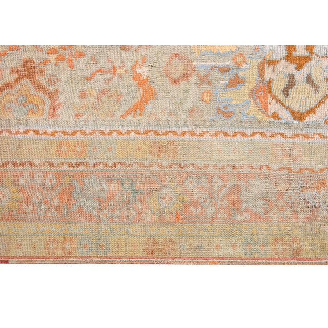 This antique Turkish Oushak rug, dating to the early 1900s, features a beautifully weathered palette of soft terracotta,...