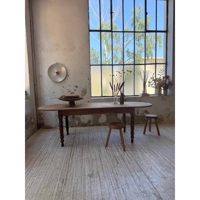 Antique 1950s pine farmhouse table. We love its large, wide oval-shaped top resting on four turned pine legs, with a...