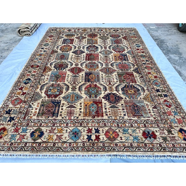 This stunning hand-knotted wool area rug features a classic Afghan Kazak tribal design. The field is filled with rows of...