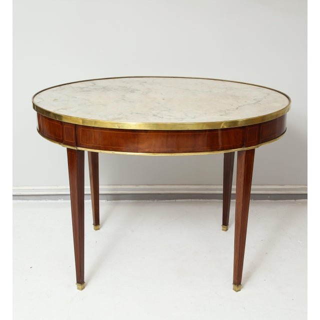 Antique French mahogany oval marble-top bronze-mounted bouillote table on tapered legs.
