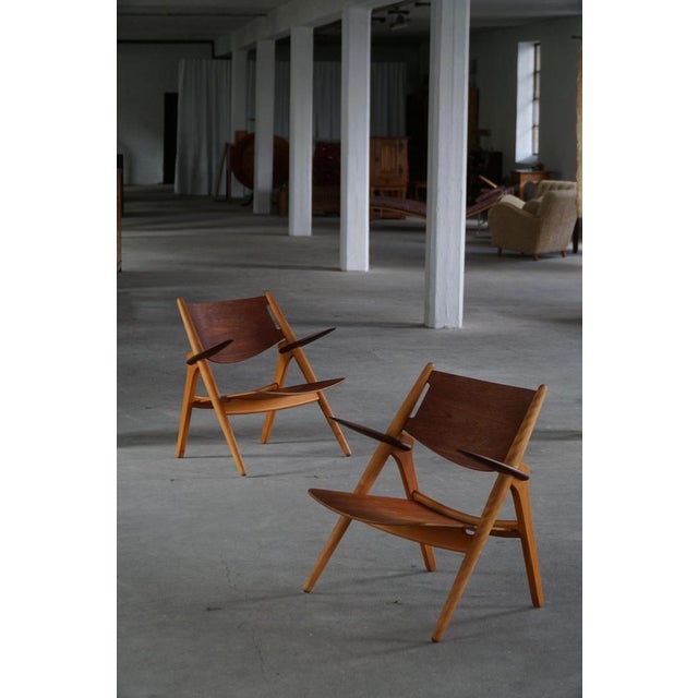 A pair of iconic ch28 "sawbuck" lounge chairs designed by hans j. Wegner in 1951 and produced by carl hansen & søn,...