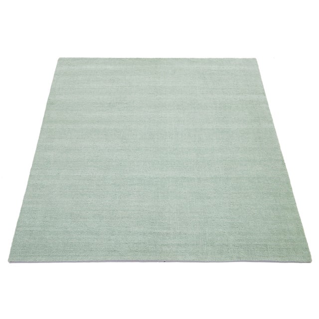 Skilled artisans thoughtfully craft this contemporary Indian hand-knotted wool rug, boasting a minimalist design. Its soft...