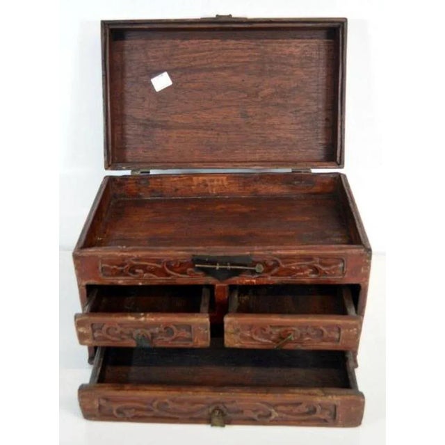 An early 20th century Chinese jewelry box made with red brown lacquered wood and iron hardware. This small rectangular box...