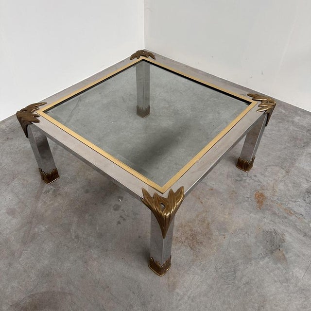 A striking 1970s hollywood regency coffee table combining polished chrome, warm brass accents and a substantial inset...