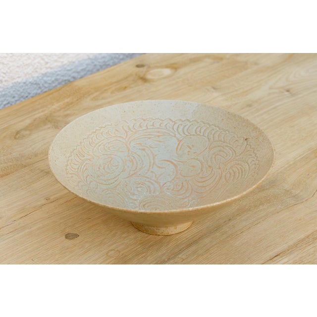 This one leads with form and surface rather than color. A wide, flared conical bowl in a soft matte ivory glaze, its...