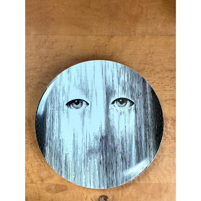 This Fornasetti Tema e Variazioni ceramic plate exemplifies the surrealist elegance for which the house is celebrated,...