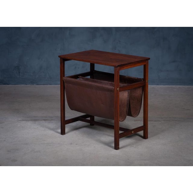 Elegant Scandinavian magazine holder from the 1960s, crafted in richly grained rosewood with a suspended leather sling. A...