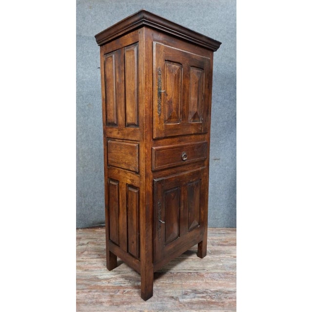 A Louis XIII style standing cabinet in solid oak, dating from the 20th century, with a narrow and elegant silhouette ideal...