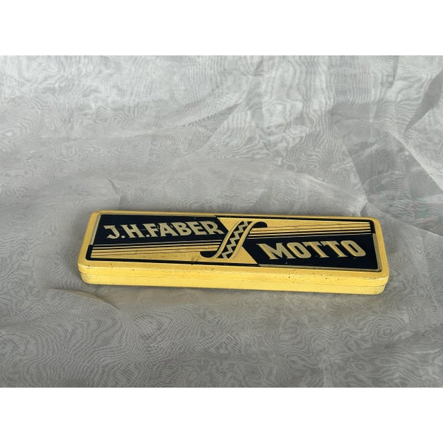 This antique tin box once held J. H. Faber Motto pencils. The vintage pencil tin is now empty, but you can use it to stash...