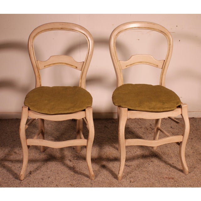 Two polychrome wooden straw-seated chairs. Model with a rounded back and double crossbar. Legs joined by wooden stretchers...