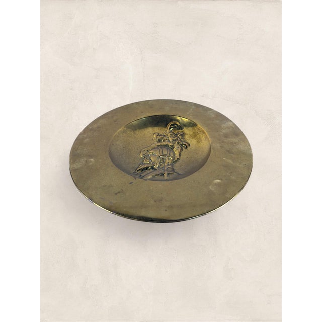 An antique English brass wall charger dating to circa 1920, featuring an embossed repoussé profile of a Renaissance-style...