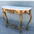 A striking vintage French style console table featuring an ornately carved giltwood base topped with a shaped white marble...