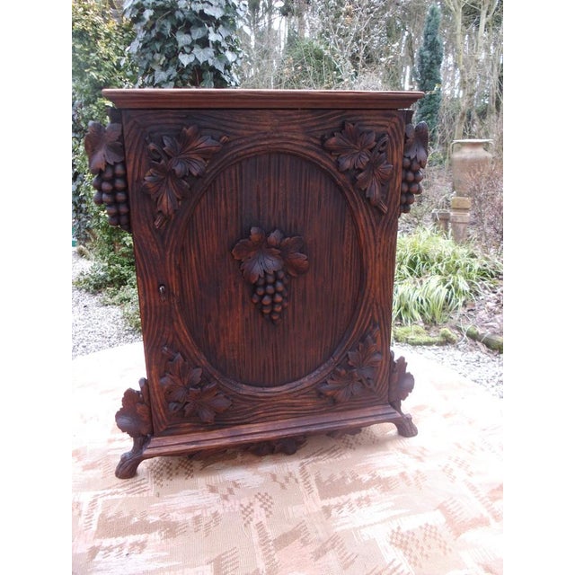 An antique, small cabinet with interior compartments, beautiful carvings, and originating from the Black Forest. Old...