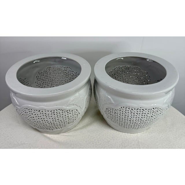 A pair of Asian pots with reticulated medallions on each side. A butterfly motif is flanked at top and bottom of each...