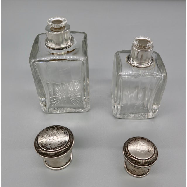 A matched pair of antique crystal scent bottles with silver collars and lids. The crystal bodies feature a beautifully cut...