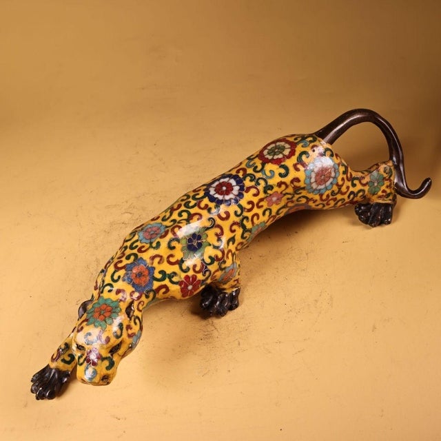 This striking sculpture depicts a leopard or feline in a dynamic, stalking pose, its body stretched low to the ground. The...