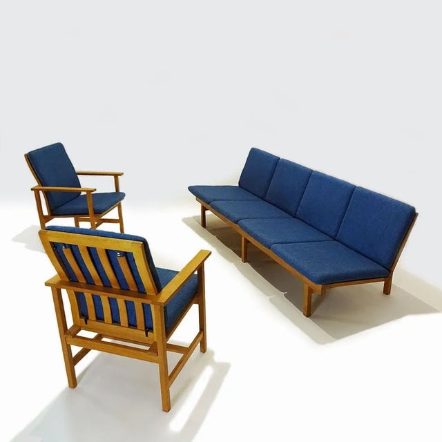A danish mid century 1950s oak and blue fabric lounge set featuring a 4 seater model 2219 bench sofa and two 2257...