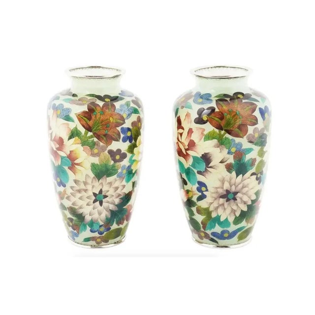 A pair of antique Japanese Meiji era enamel vases. The vases are covered with polychrome enamel foliage and floral...