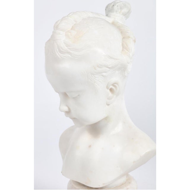 beautifully carved, the serene marble sculpture depicting a young girl's bust with three quarter face in a downward gaze;...