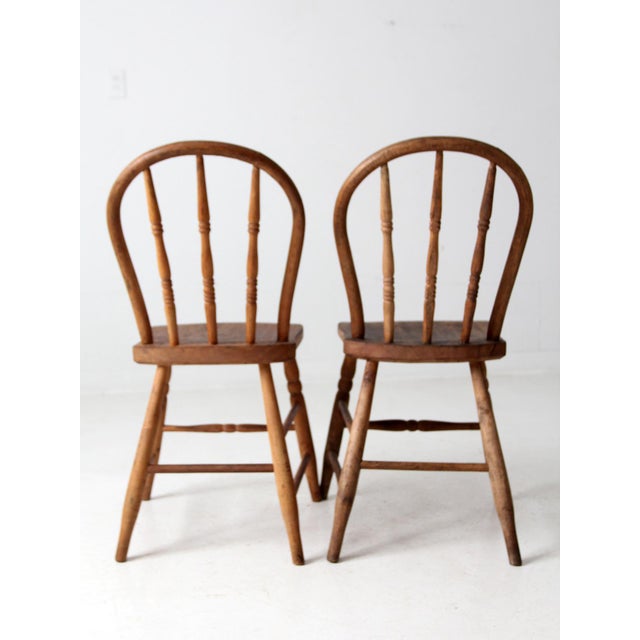 This is a pair of antique bow back farmhouse chairs. The Windsor style dining chairs feature round bow backs with turned...