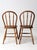 This is a pair of antique bow back farmhouse chairs. The Windsor style dining chairs feature round bow backs with turned...