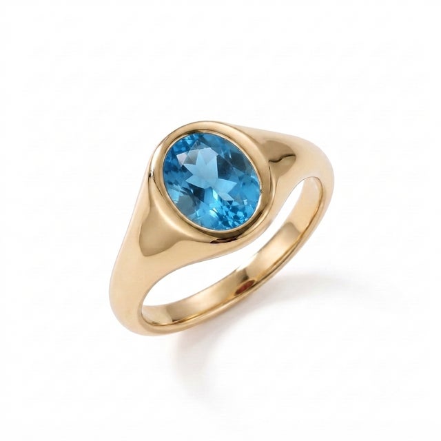 Make a refined statement with this elegant Natural Swiss Blue Topaz Signet Ring, showcasing a brilliant 7 x 5 mm oval-cut...