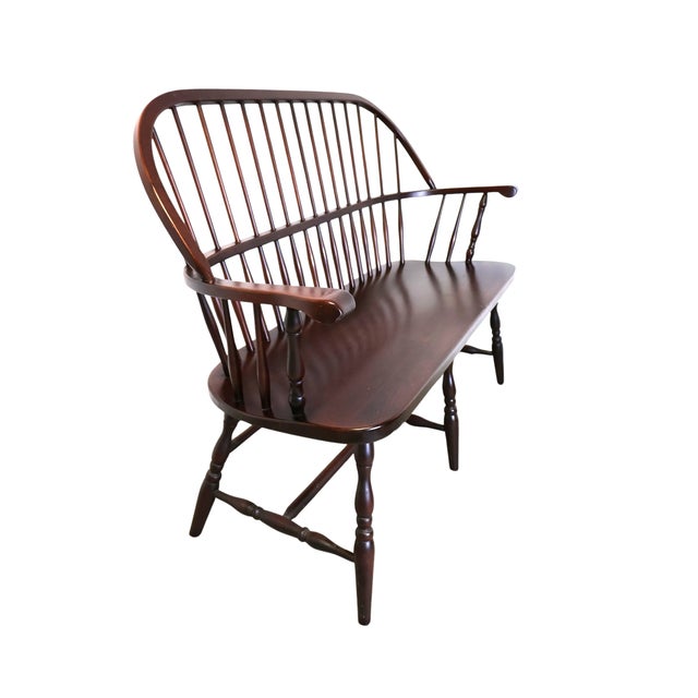 Vintage American Windsor settee crafted of solid poplar with a warm reddish-brown finish, featuring a graceful continuous...