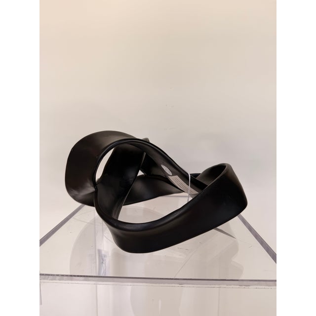 Contemporary abstract sculpture featuring a flowing, ribbon-inspired design in a rich matte black finish. Its graceful,...