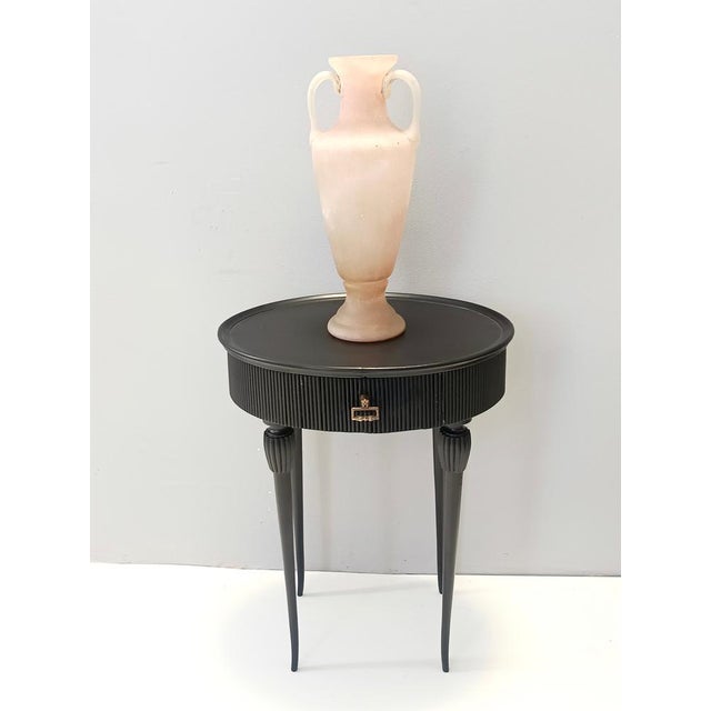 Made in Italy, 1950s. It features an ebonized beech frame with a brass handle. The edge is ribbed and its legs are in...