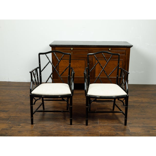 A pair of vintage Chinese Chippendale style black faux bamboo armchairs from the mid 20th century, with new upholstery....